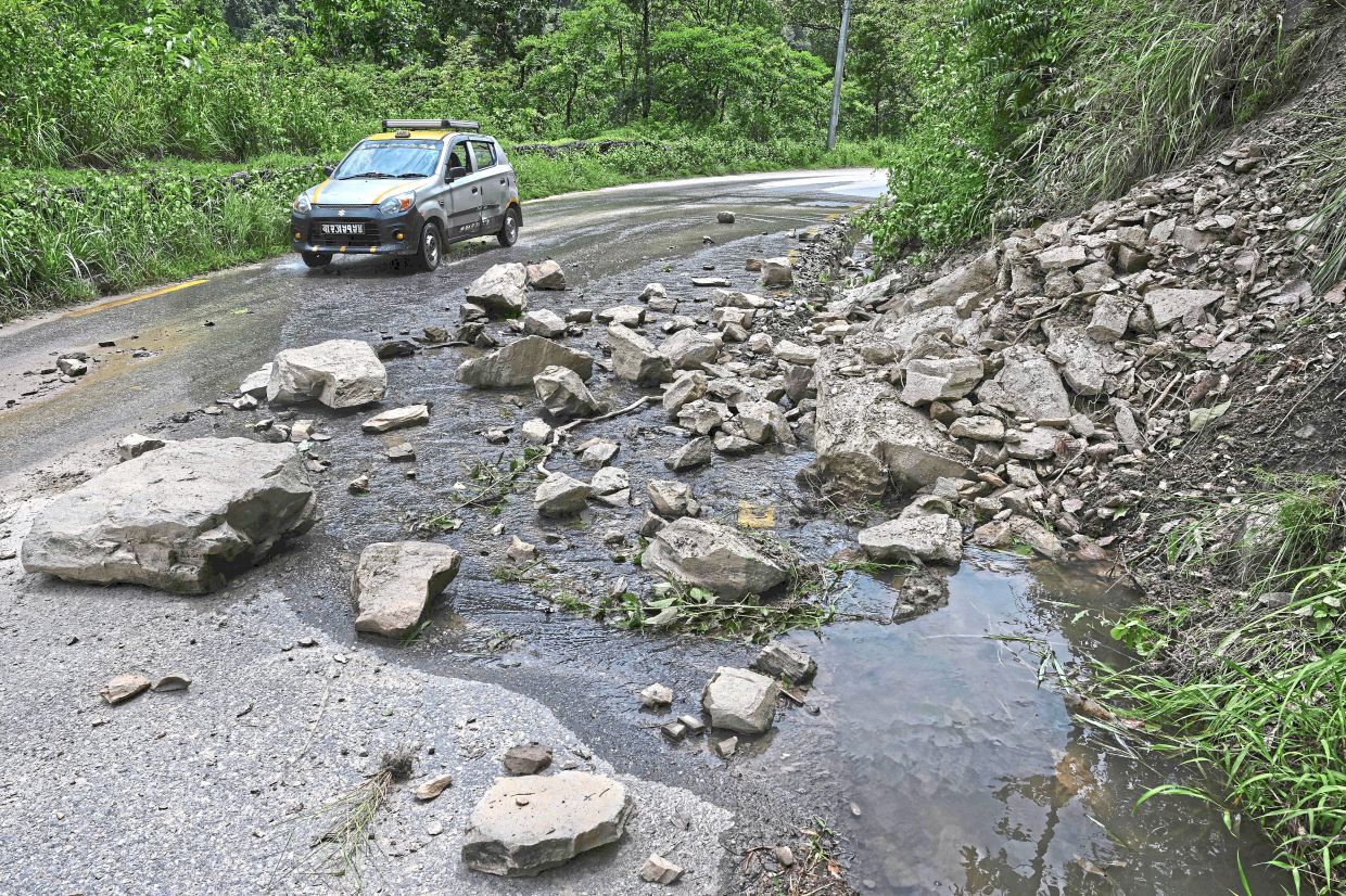 Precarious situation: A vehicle passing through a landslide-prone area on the Arniko Highway in Nepal’s Sindhupalchok district. — AFP