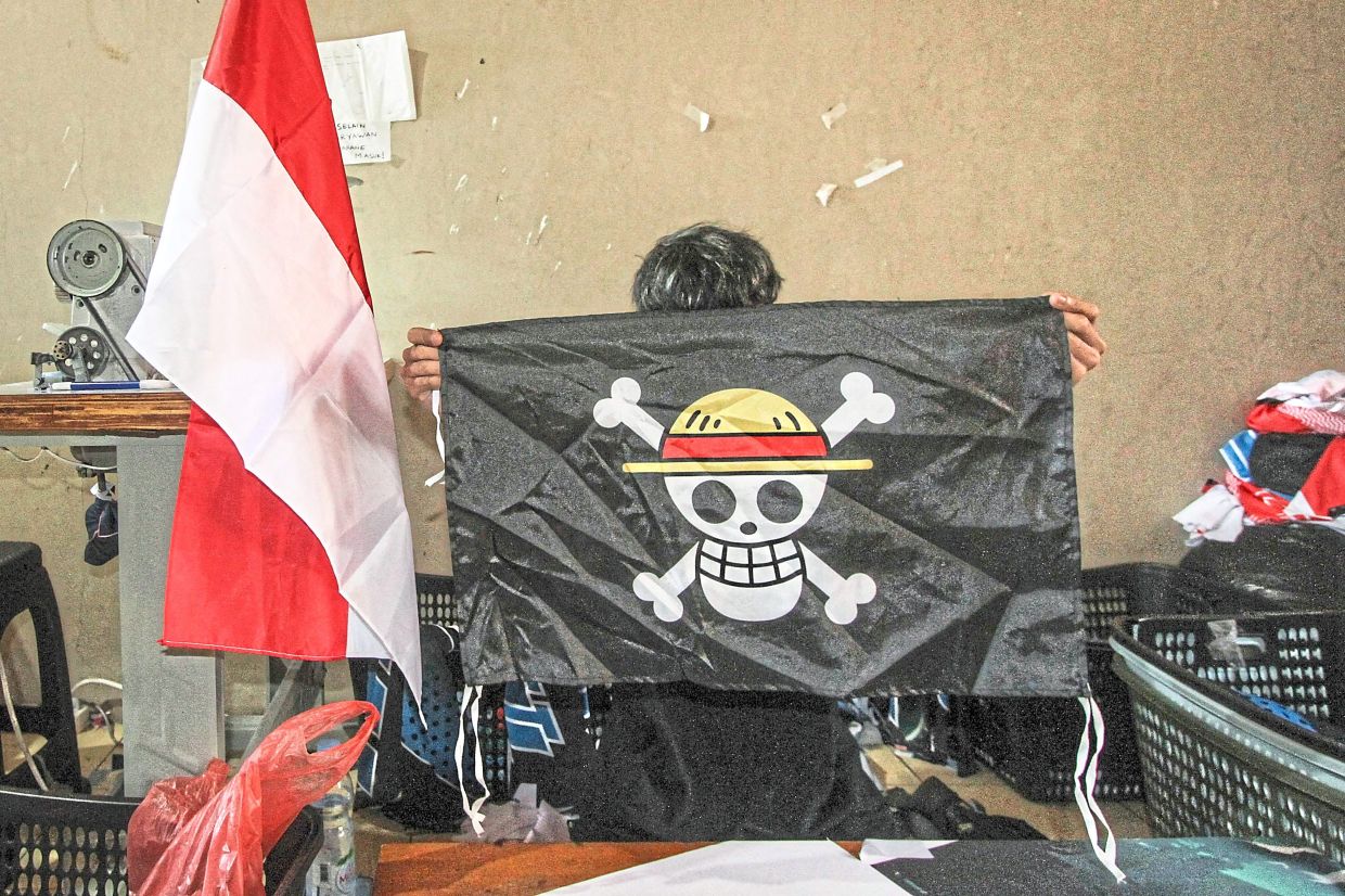 Hot-seller: A worker holding a replica of the pirate flag at a T-shirt workshop in Karanganyar, Central Java. — AFP 
