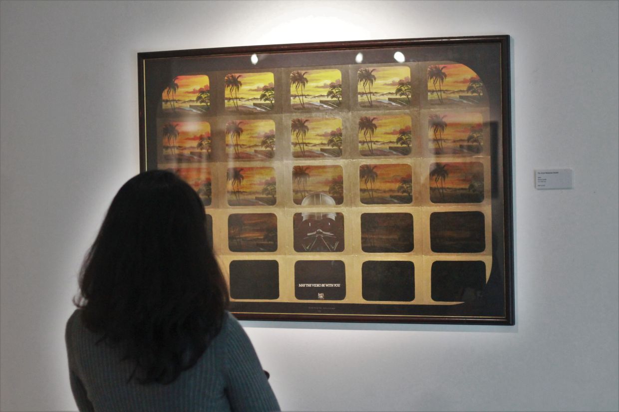 A visitor observes Unglehrt's mixed-media artwork titled 'The Great Malaysian Sunset', 1989, featuring Darth Vader in a series of kampung scenes. Photo: The Star/M. Irsyad 