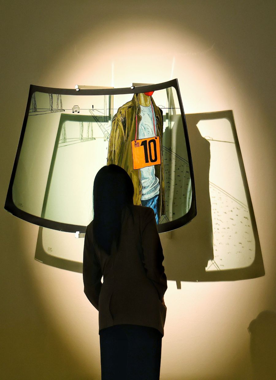 A visitor views one of five windshield panels from Azim’s 'Langkah Terasing' series, highlighting roadside fruit sellers in the city’s busy traffic areas. Photo: The Star/Muhamad Shahril Rosli