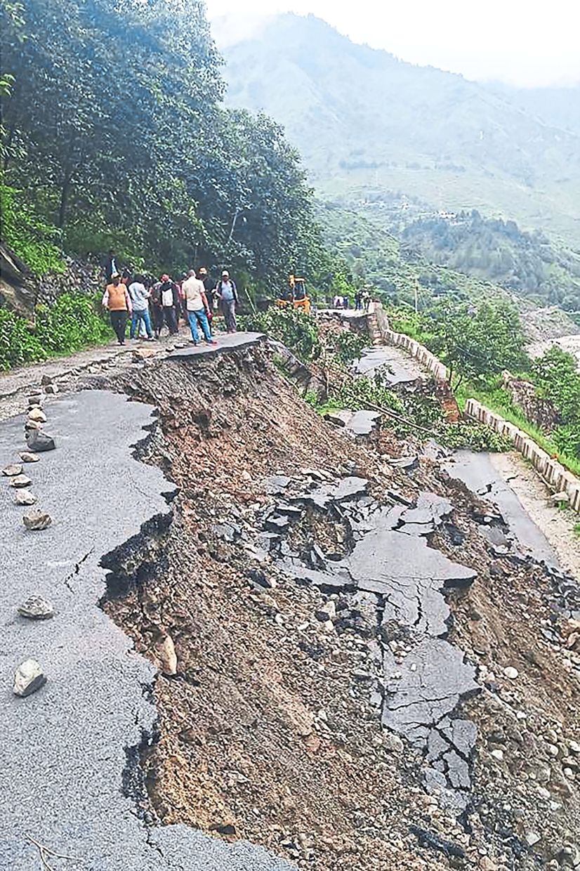 Race against time: Villagers standing beside a road partially destroyed by heavy rains near India’s Uttarakhand state. — AFP