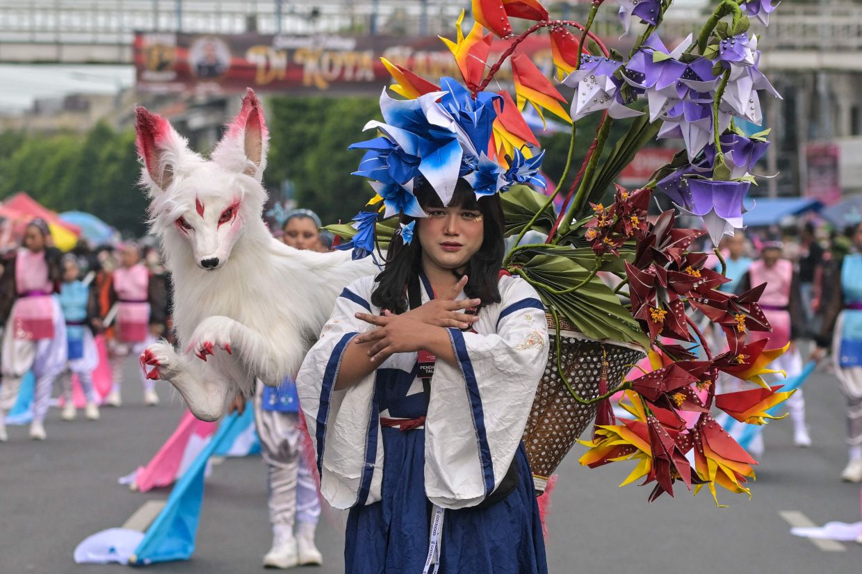 An Indonesian performer dressed in an origami-themed costume takes part in a 3.6-kilometer parade during the Jember Fashion Carnival in Jember, eastern Java island, on Sunday, August 10, 2024. -- Photo by Juni KRISWANTO / AFP