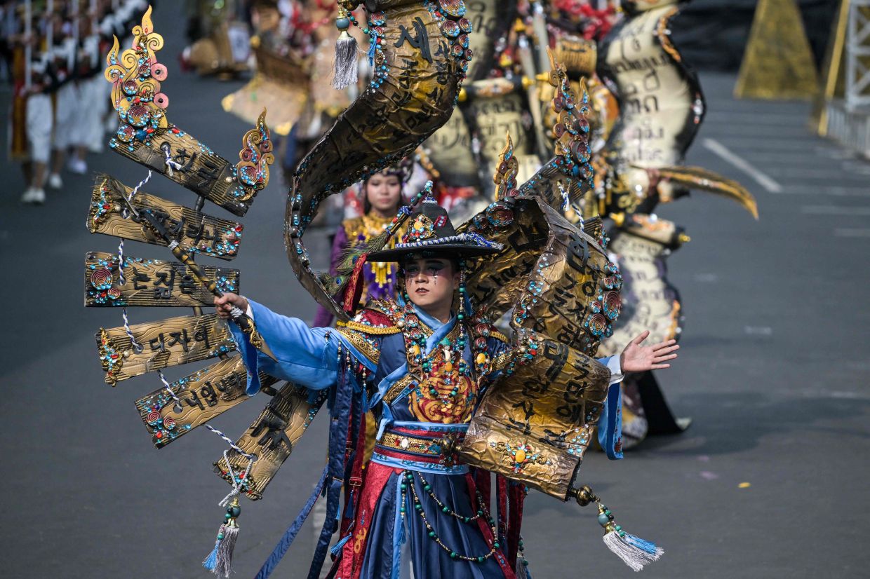 An Indonesian performer dressed in allograph-themed costumes takes part in a 3.6-kilometer parade during the Jember Fashion Carnival in Jember, eastern Java island, on Sunday, August 10, 2024. -- Photo by Juni KRISWANTO / AFP