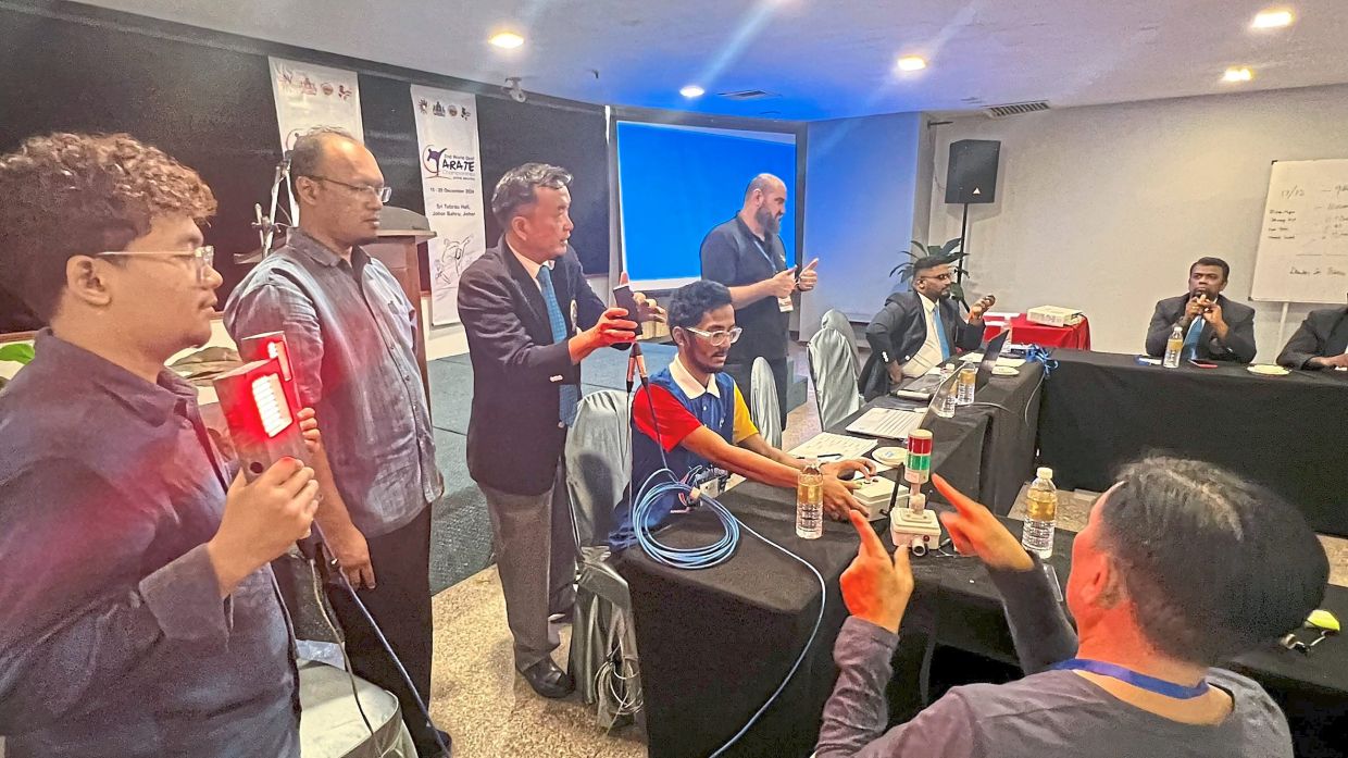 Jaysuman (second from left, standing) with Chief Judge Chok Kong Yu (third from left, standing) showcasing the Neonkumite system to a judging panel. — JAYSUMAN PUSPPANATHAN