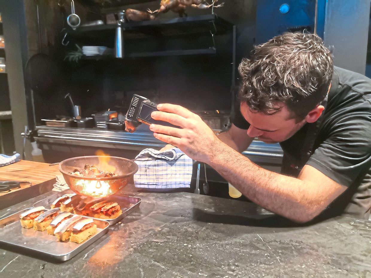 Agnes Restaurant prepares sardine toast using hot air from burning coals.