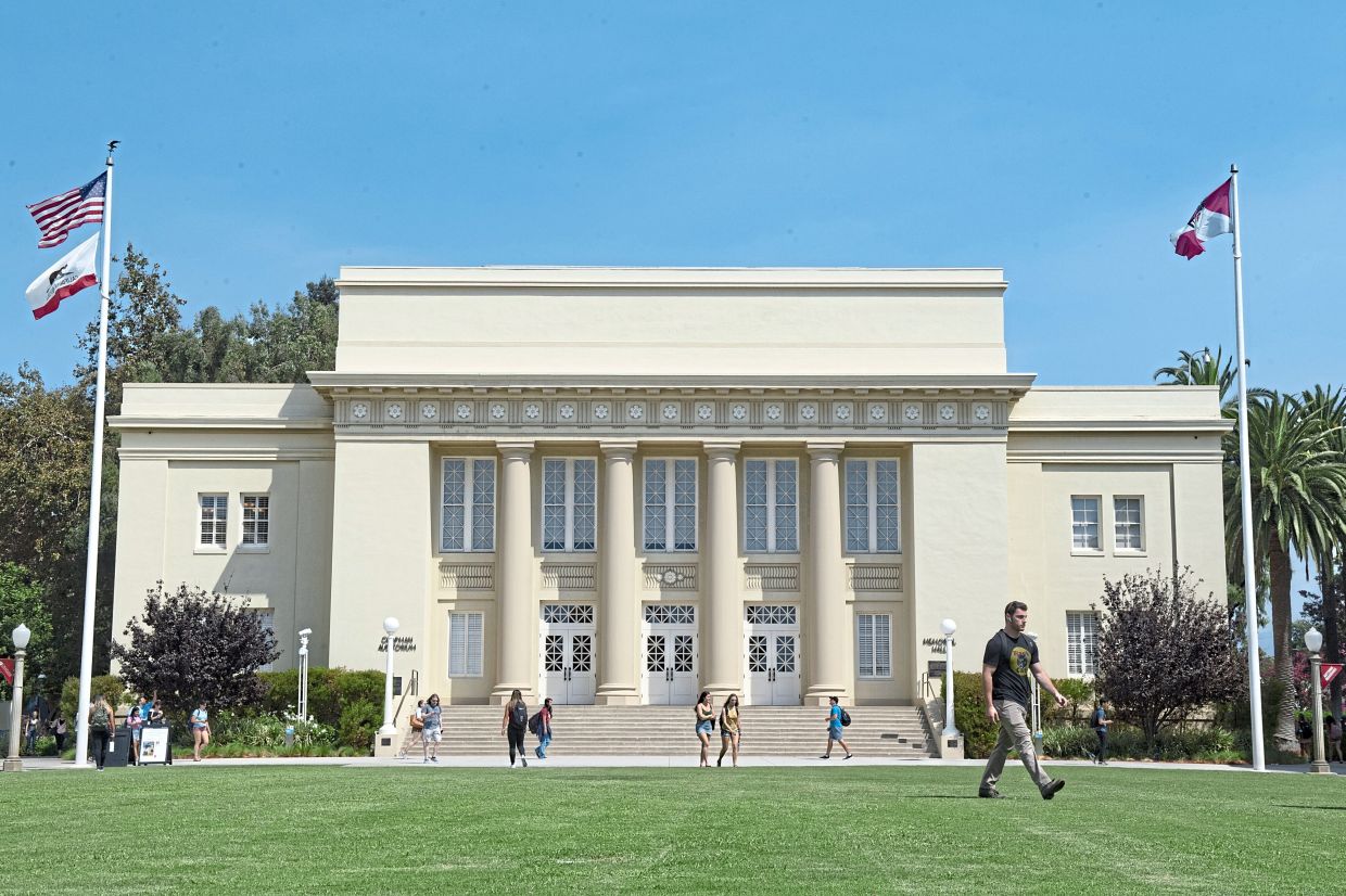 Students cross the Bert Williams Mall in front of Memorial Hall at Chapman University.