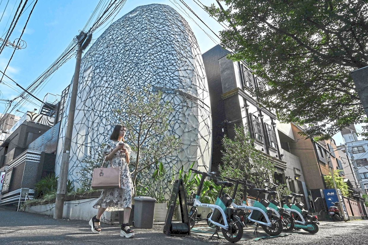 A pedestrian passes Kinoko’s blue rope–wrapped egg-shaped home 'Natural Eclipse' in Shibuya, Tokyo. Photo: AFP