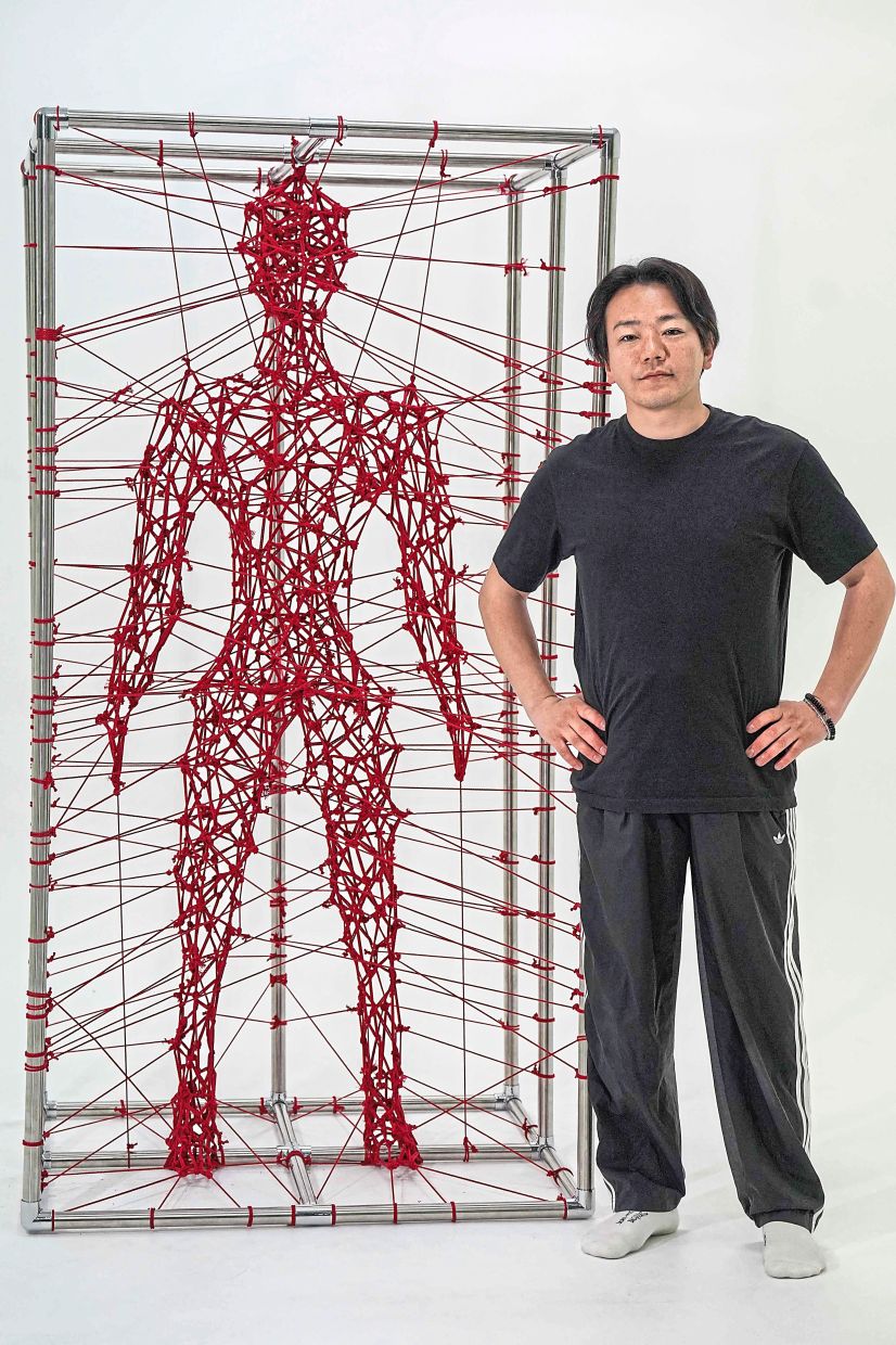 Kinoko, one of Japan’s leading shibari (rope art) artists, poses beside a rope-sculpted human figure in his Tokyo studio. Photo: AFP 
