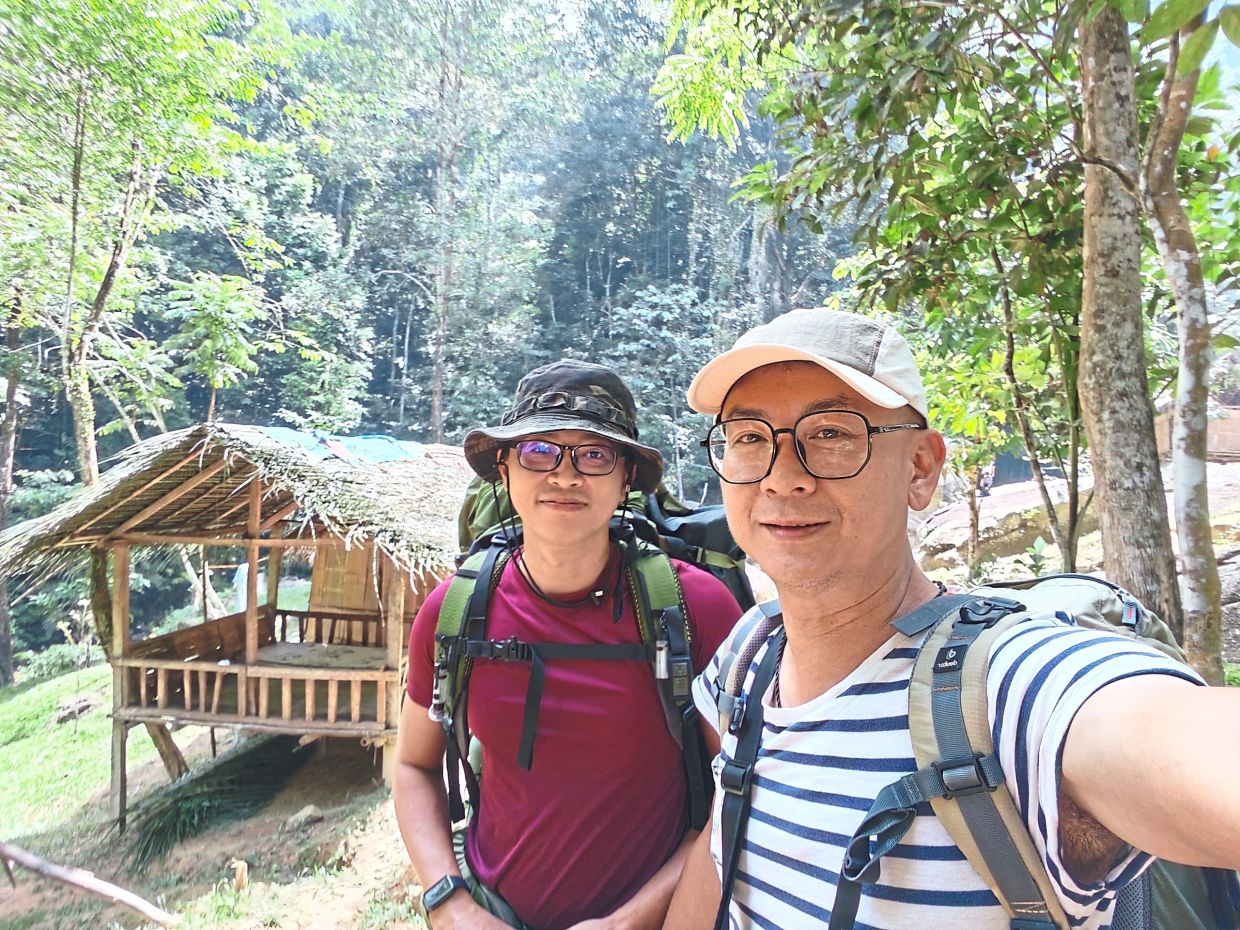 At the campsite with their Orang Asli bamboo hut – their temporary home – in the background.