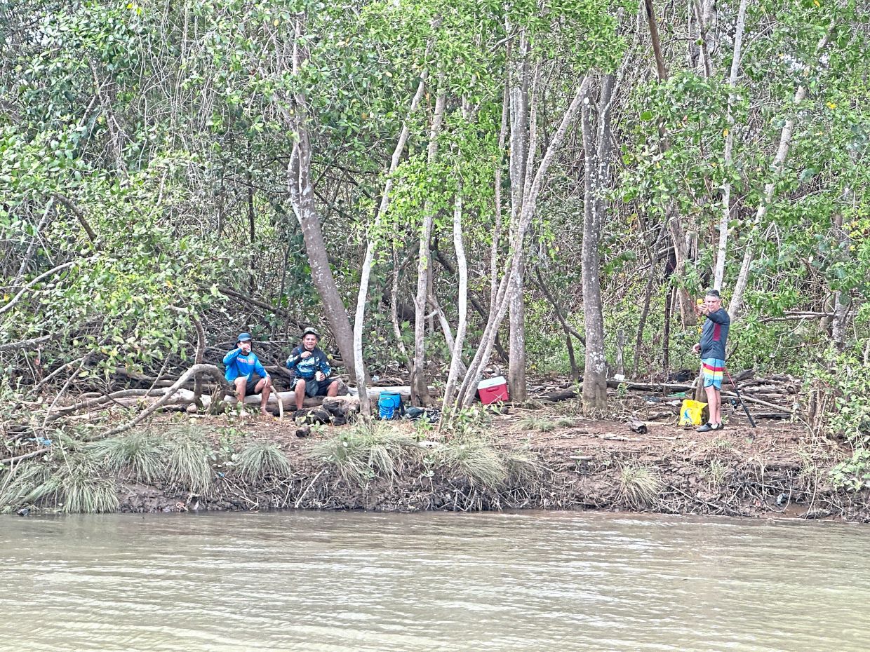 Friends taking a break in the shade of the mangroves, with their coolers close by.
