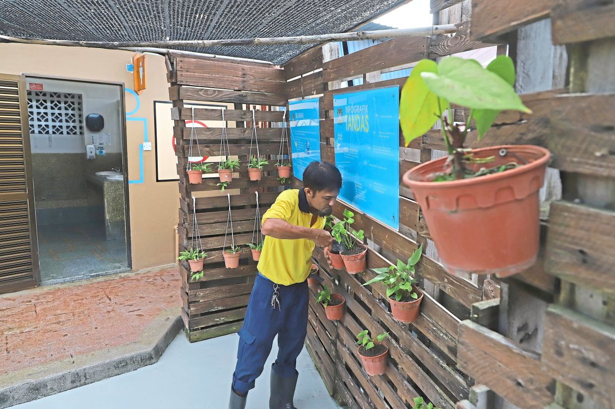 Sohaimi tending to plants at the toilet facility he maintains at Air Itam Market.