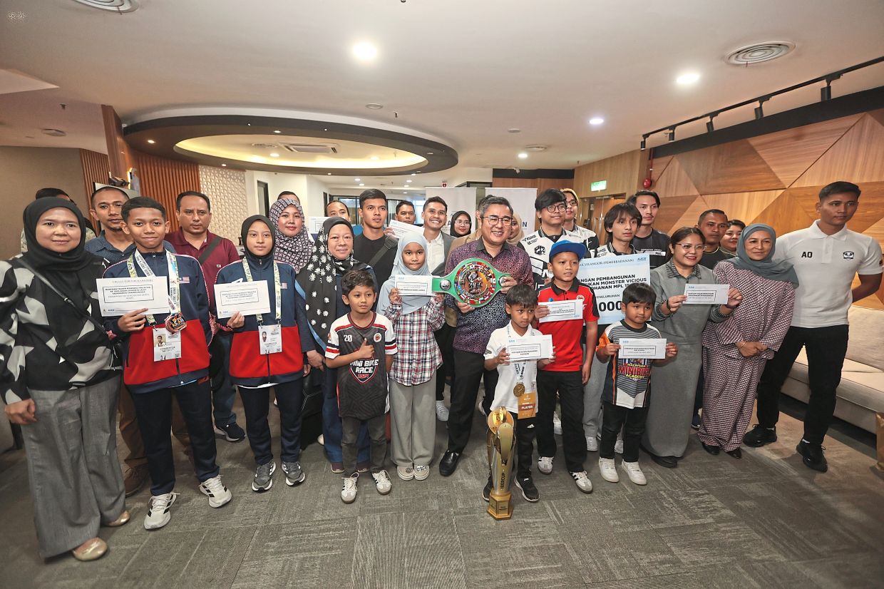 Ahmad Azri (front row, seventh from left) holding a boxing championship belt while posing with all the grant recipients at Bangunan Darul Ehsan in Shah Alam. — Photos: LOW BOON TAT/The Star