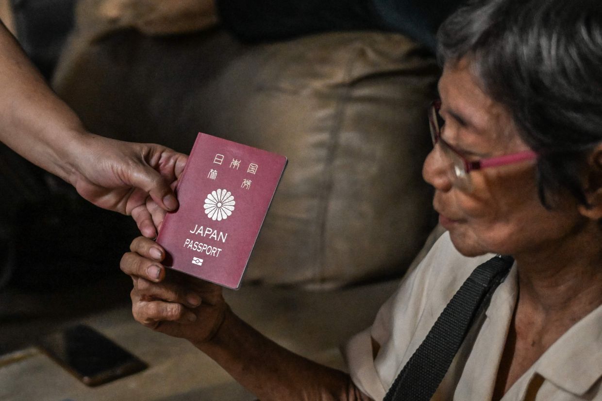 Maria Corazon Nagai showing her Japanese passport at her home in Manila. - AFP