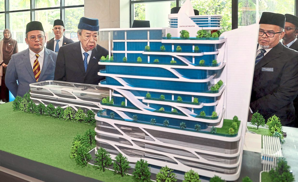 Maritime milestone: Selangor Ruler Sultan Sharafuddin Idris Shah (centre) taking a closer look at the model of the Light Dues Tower. Looking on is Amirudin (left). — KK SHAM/The Star