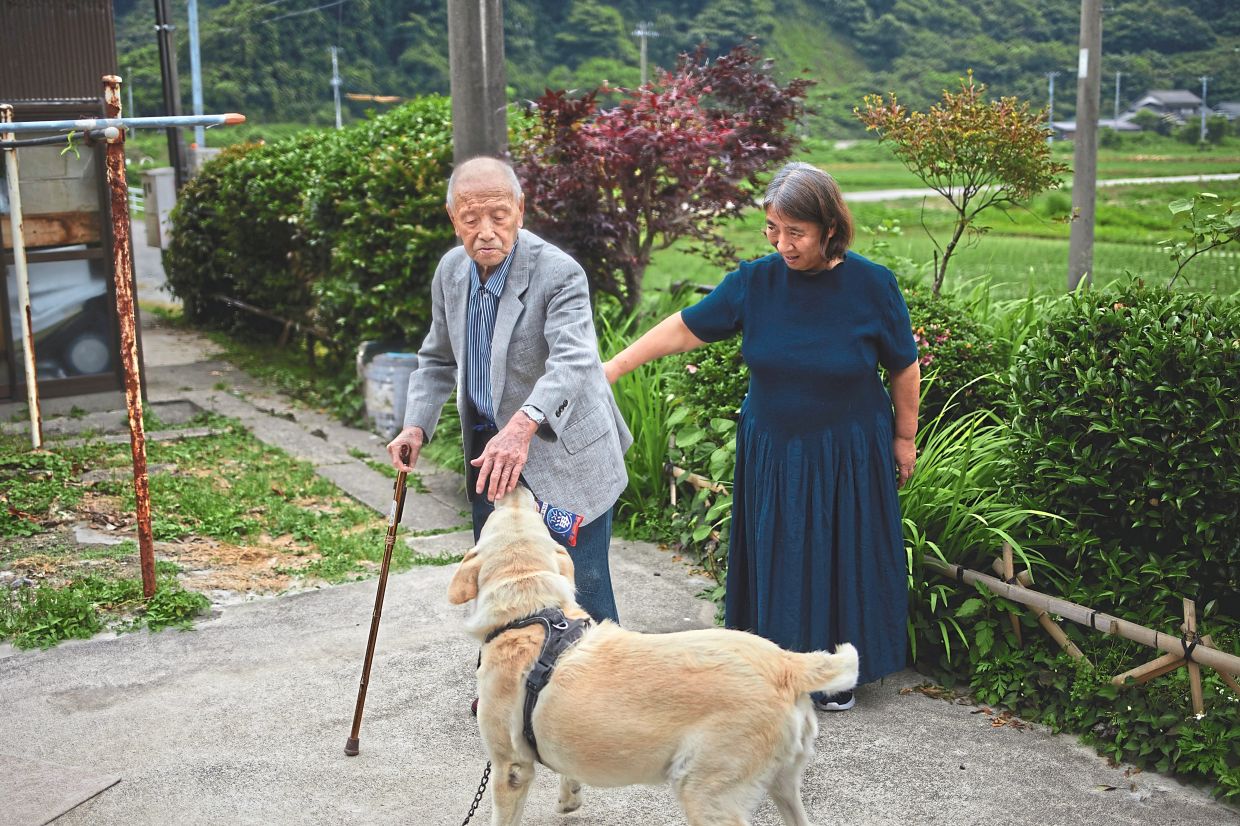 Sato, 105, outside his home with his daughter-in-law, Kuniko and his dog in Osonogo, a village in Japan’s northern prefecture of Niigata.