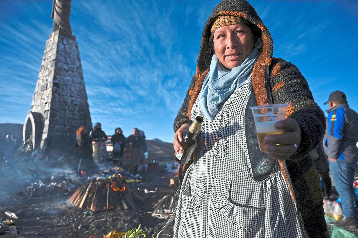 An Aymara woman offering beer during the celebration of Pachamama in La Cumbre, Bolivia. — Photos: Reuters