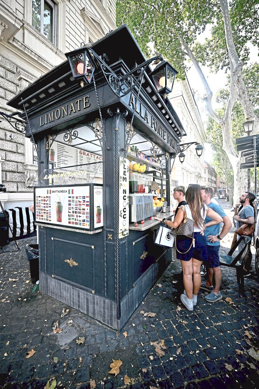 Customers queue to order a 'Grattachecca' at a kiosk in Rome on August 12, 2025. Italy is facing extreme heat until mid-August as temperatures above 40 degrees centigrade is gripping the entire country at least until the August 15th bank holiday weekend. (Photo by Filippo MONTEFORTE / AFP)