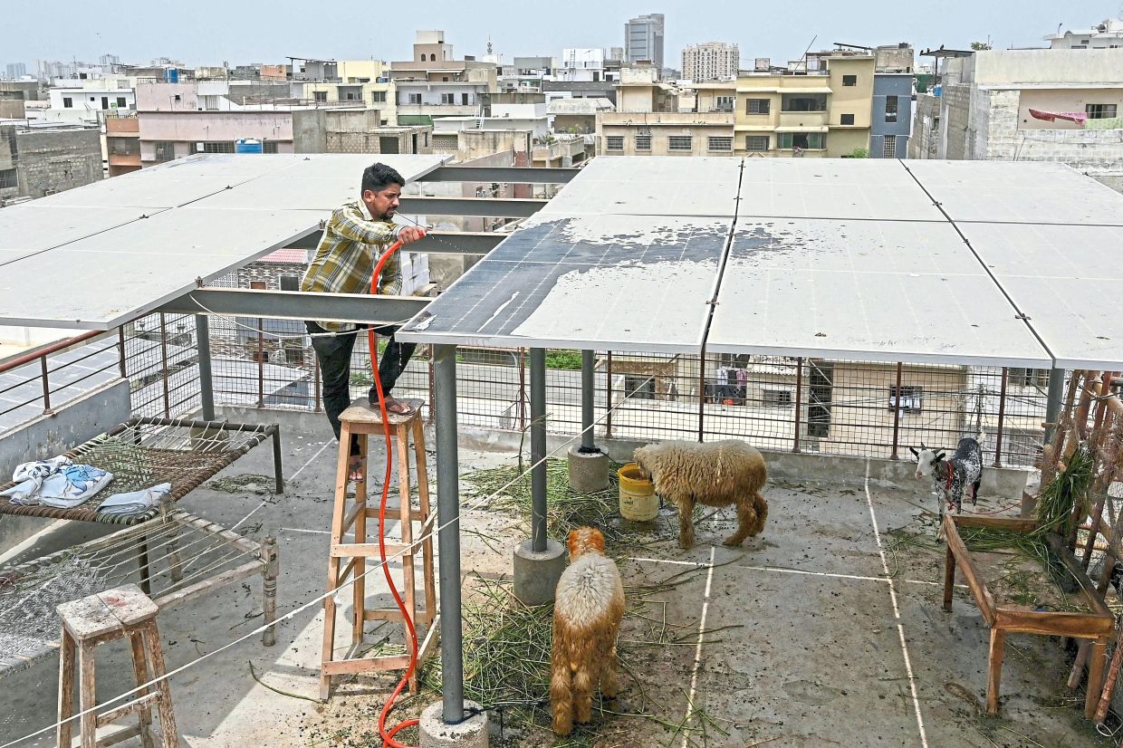 Arsalan Arif, a local businessman, cleaning solar panels installed on his house’s rooftop in Pakistan’s port city of Karachi. — AFP