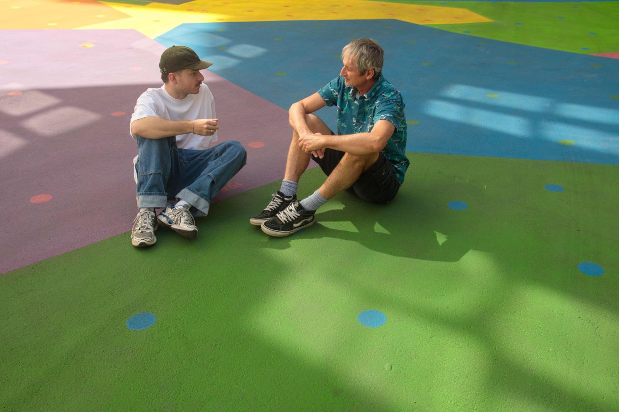 Griessler, a member of artist group Holla Hoop, and Prof Hans-Peter Hutter (right) sit on the ground over the colourfully painted courtyard of the Heidi Horten museum in Vienna, Austria. Photo: AFP