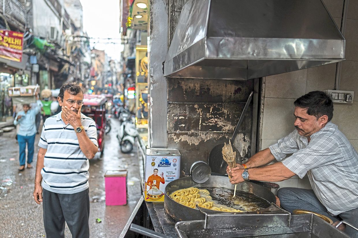 A worker preparing jalebi, a popular sweet snack, at a street stall.