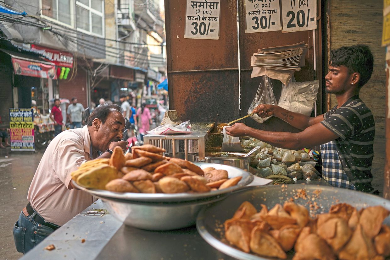 Naughty delights? A man enjoying a samosa at a street stall in New Delhi. A government advisory noting the high fat and sugar levels in many popular snacks was seen by some as an attack on India’s beloved street food.