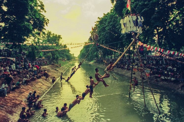 Captured in 1995, this moment shows climbers navigating a grease-slicked pole in a demanding test of strength, balance and collective effort. - Photo: The Jakarta Post/ANN