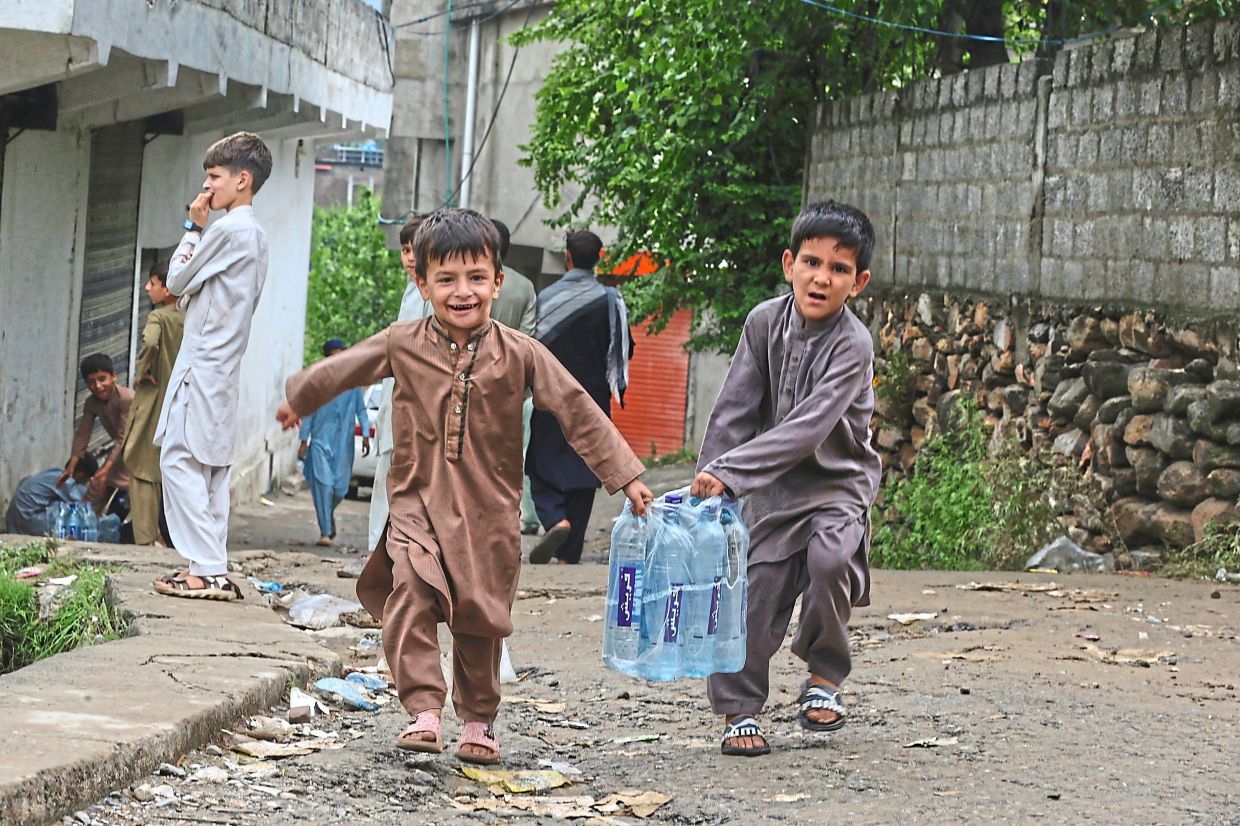 Children with water bottles at a relief camp set up in Pishoreen village. — AFP/AP