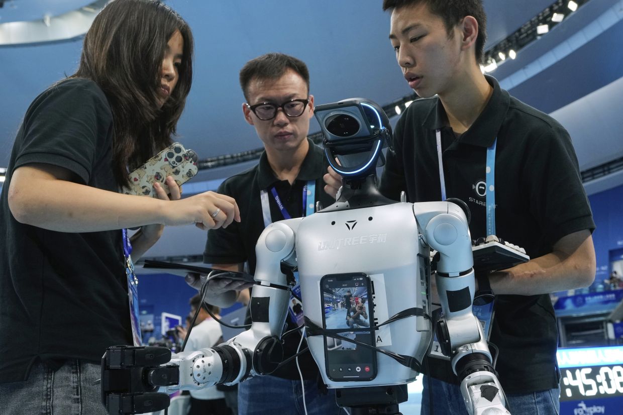Technicians check a robot after it fell during an event during the World Humanoid Robot Games held in Beijing, China, Saturday, Aug. 16, 2025.