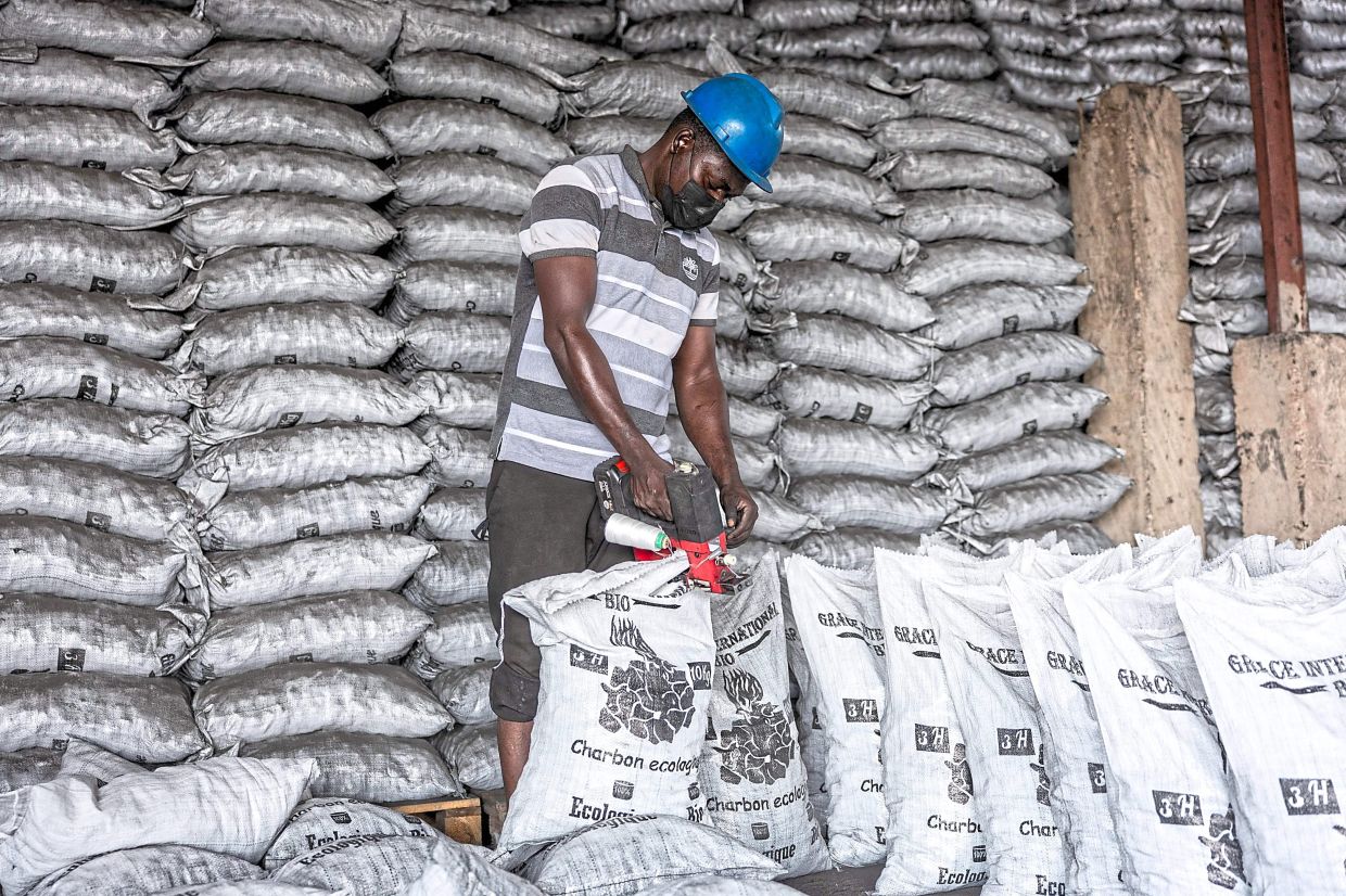 A worker seals bags containing coal pebbles.
