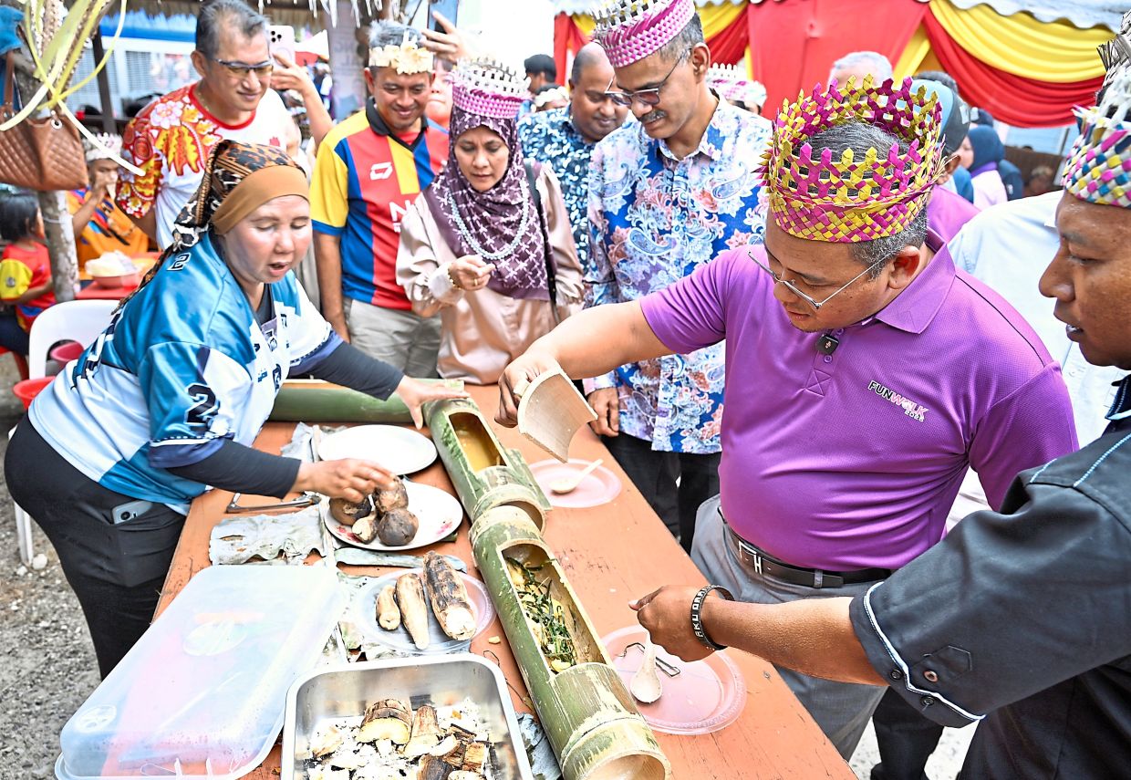 Selangor Mentri Besar Datuk Seri Amirudin Shari (right) trying out some of traditional food during the Orang Asli Festival at Kampung Orang Asli Kelinsing in Sepang.