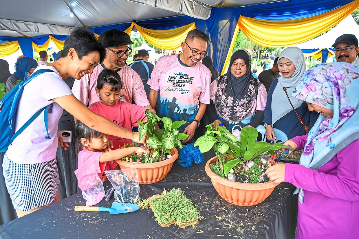 Mohd Fauzi (centre) and MBPJ Landscape Department director Dr Badrulzaman Jaafar (fourth from left) engaging with Michelle Chong, (left) and her two daughters Yow Yoong En and Yow Yoong Ler at the mini landscape and terrarium workshop in Taman Jaya.