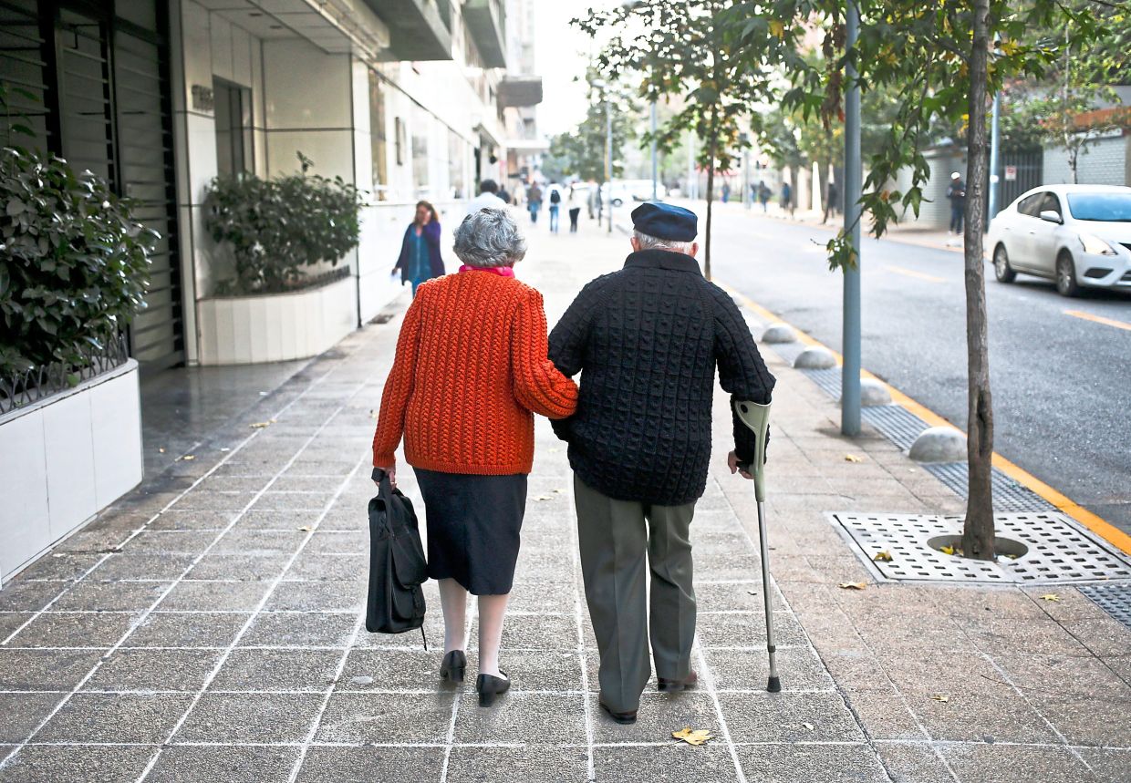 A couple walk on a sidewalk in Santiago, Chile. — ESTEBAN FELIX/AP