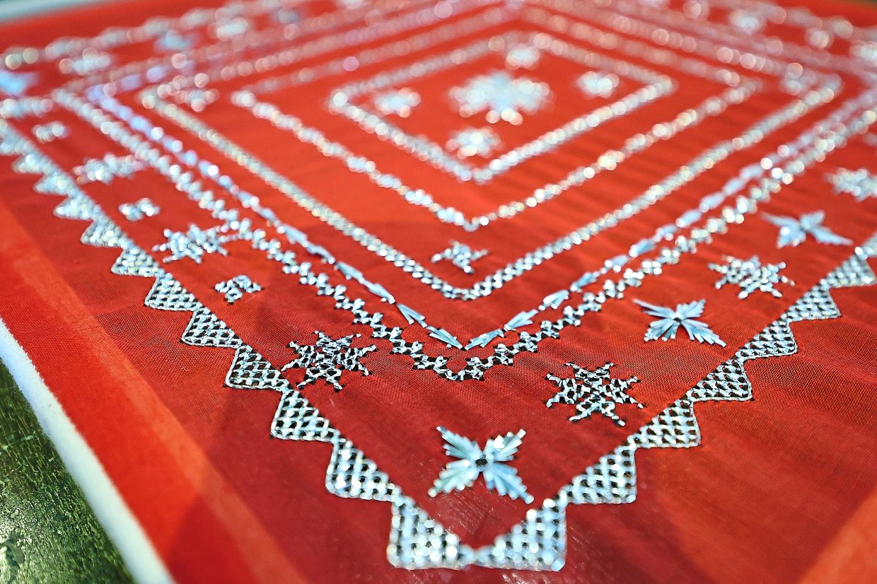 Sarawak keringkam features intricate designs embroidered by hand in gold or silver thread on delicate fabric. (Right) A keringkam piece featuring the ‘tali air kaki lipan’ (centipede legs) border and a floral motif.