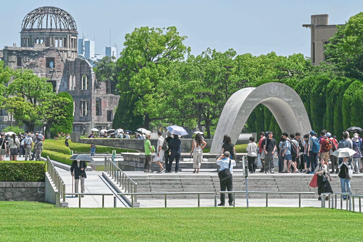 People visiting the Memorial Cenotaph at the Hiroshima Peace Park in Hiroshima; and (below) residents preparing to have their funeral portraits taken at the Hapcheon Atomic Bomb Victim Welfare Centre in South Korea. — AFP
