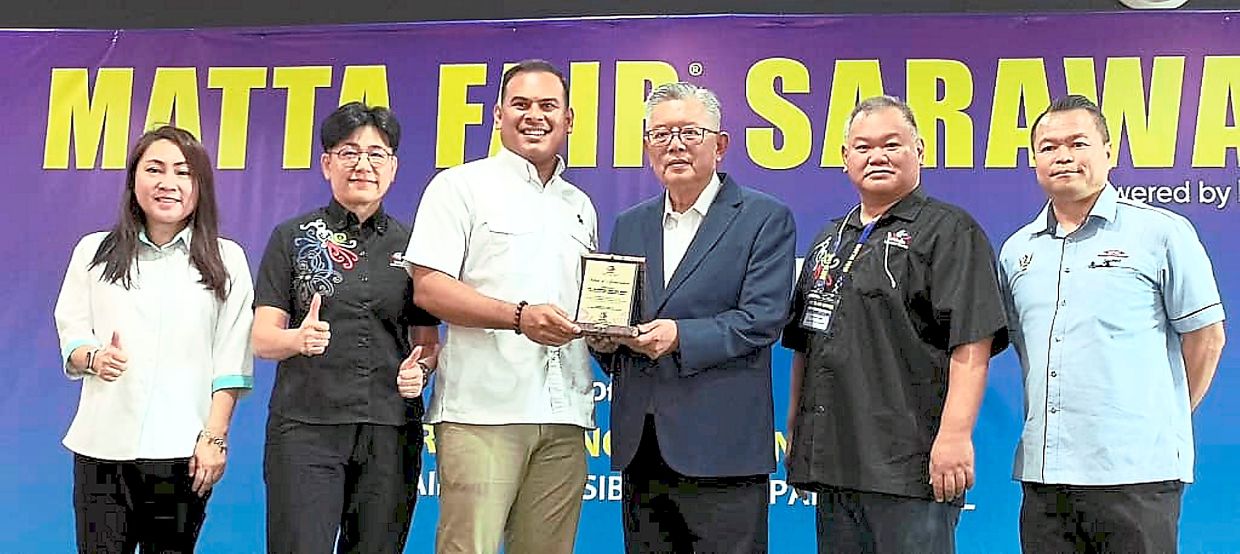 Awadh (third from left) presenting a souvenir to Ting while Ling (second from right) looks on during MATTA Fair Sibu.