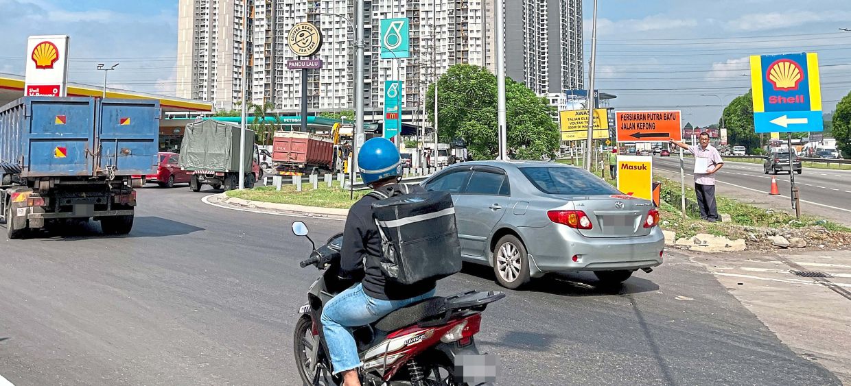 Yee (right) showing one of the two small signboards on the traffic diversion to Persiaran Putra Bayu that can be easily missed.