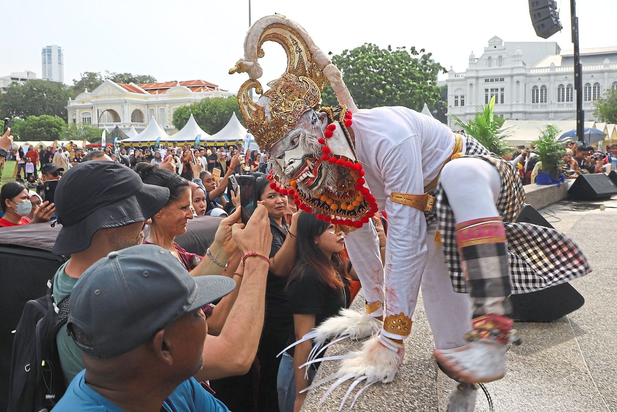 Visitors taking photos of an elaborately dressed performer from Indonesia’s KRI Bung Tomo.