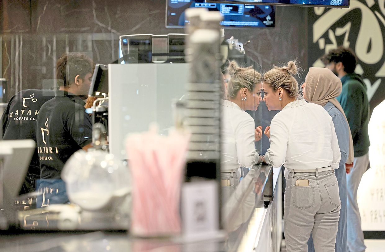 A customer peers into a display case of desserts at a Yemeni cafe.