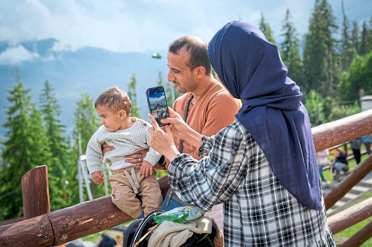A woman wearing a headscarf taking a picture of her child on Gubalowka.