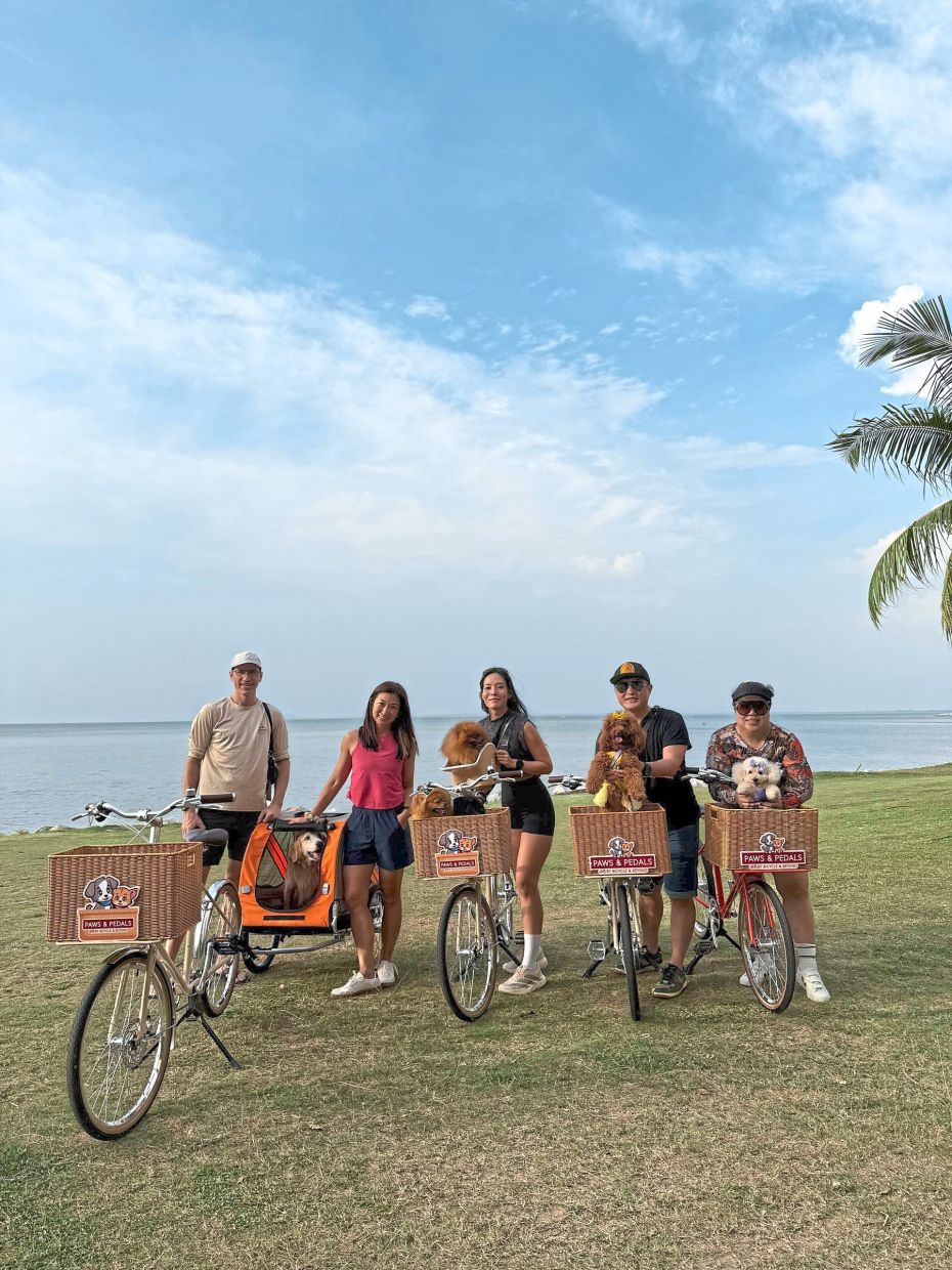 Siew (second from left) with her bicycle rental business in Penang that enables dog owners to cycle around with their pets. Chelsy is pictured here in the covered carriage.