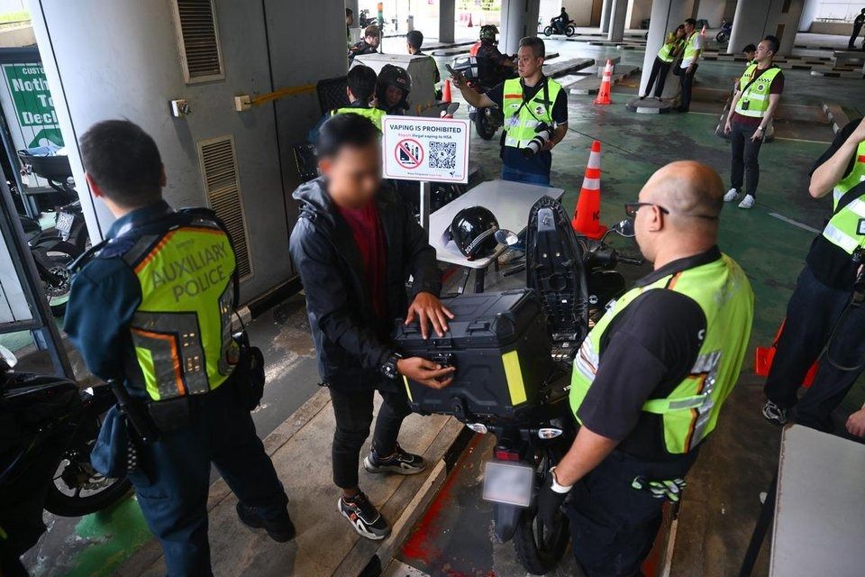 Officers conducting checks on motorcyclists at Tuas Checkpoint on Aug 22. - Photo: ST