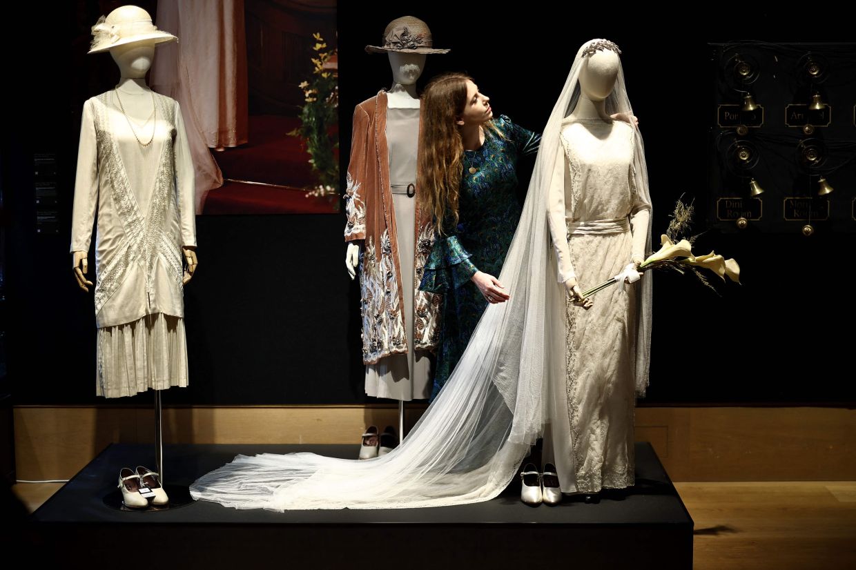 An auction house staff member looks at a wedding dress belonging to the character Lady Mary from the 'Downton Abbey' series during a press preview. Photo: AFP