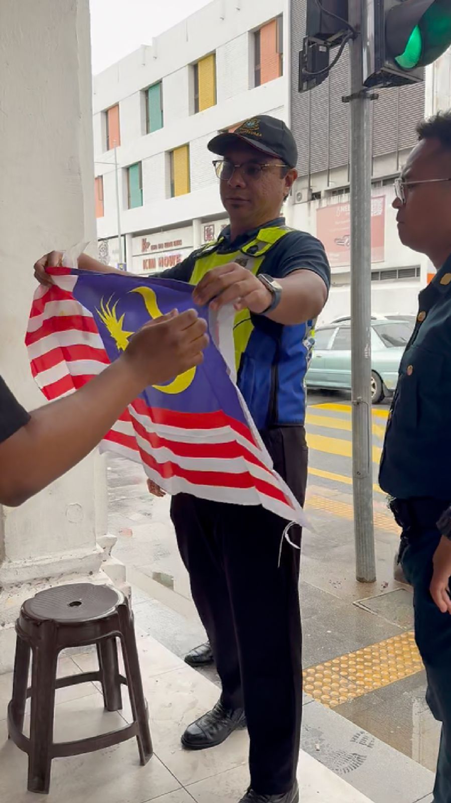 MBPP Enforcement Director Noorazrein Noorazlan Ong (left) giving a local shop a new Jalur Gemilang in George Town, Penang.