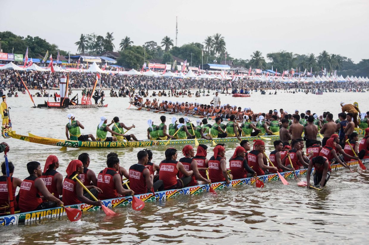Participants gather during the Pacu Jalur longboat race festival on the Kuantan River in Kuantan Singingi Regency, Riau Province. Armed with colourful oars, rowers pack into long boats in western Indonesia, paddling furiously in front of race crowds swelled by the viral success of a young boy famous for his dancing at the front of the traditional vessels. -- Photo by Wahyudi / AFP