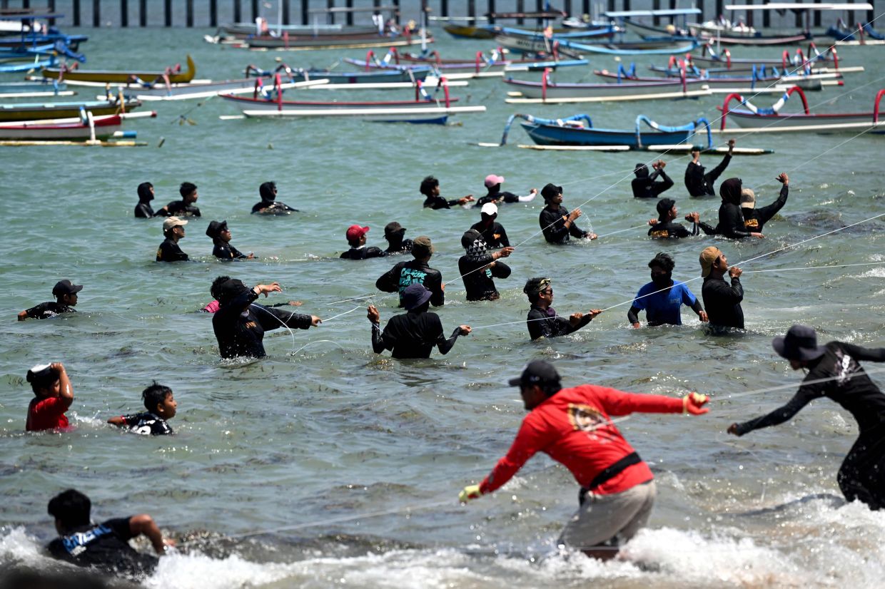 People fly traditional kites during a kite festival at Mertasari beach in Denpasar on Indonesia's resort island of Bali, on Sunday, August 24, 2025. -- Photo by SONNY TUMBELAKA / AFP