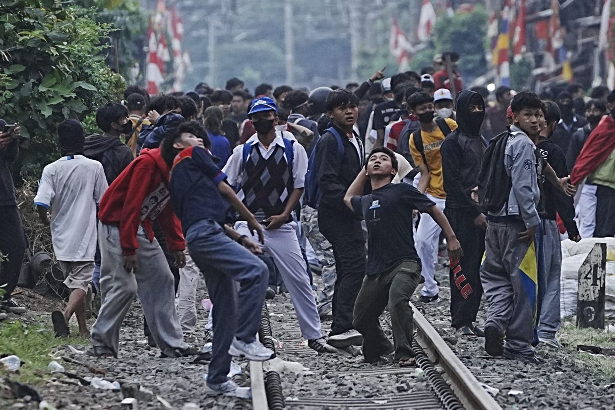 Protesters throw rocks towards riot police during a protest against lavish allowances given to parliament members, in Jakarta, Indonesia, Monday, Aug. 25, 2025. -- AP Photo/Achmad Ibrahim