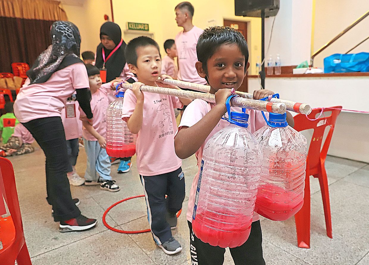 Teamwork at play with Muhammad Saad (front) and his friend carrying containers on wooden sticks during a game.