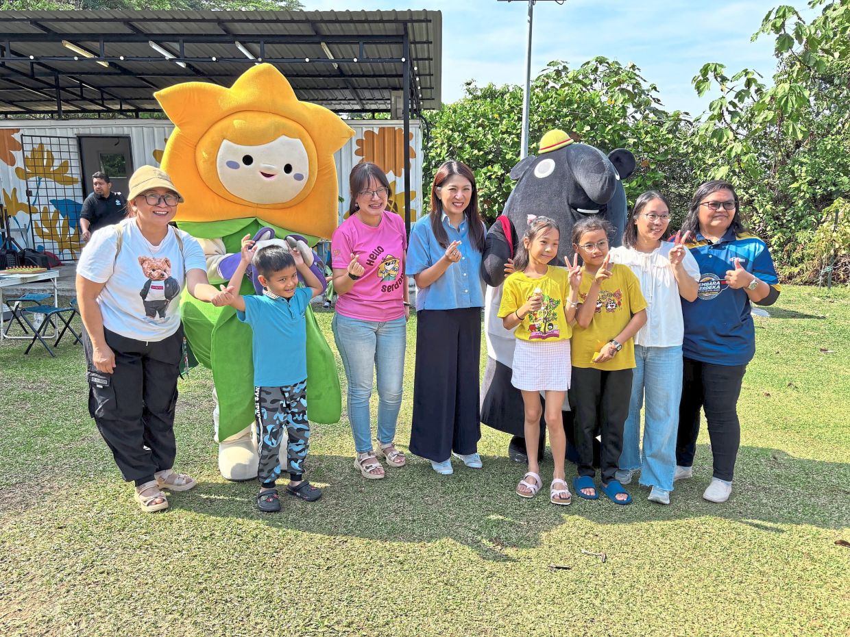 Siew Ki (third left), Yeo (centre) and Suzanah (second right) posing for a group photo with attendees and two mascots – Bling Bling and Bumi.