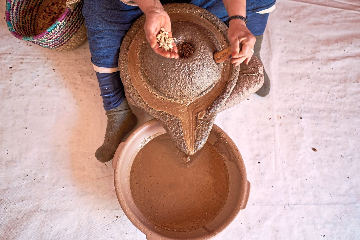 A woman pours argan nuts to extract oil.
