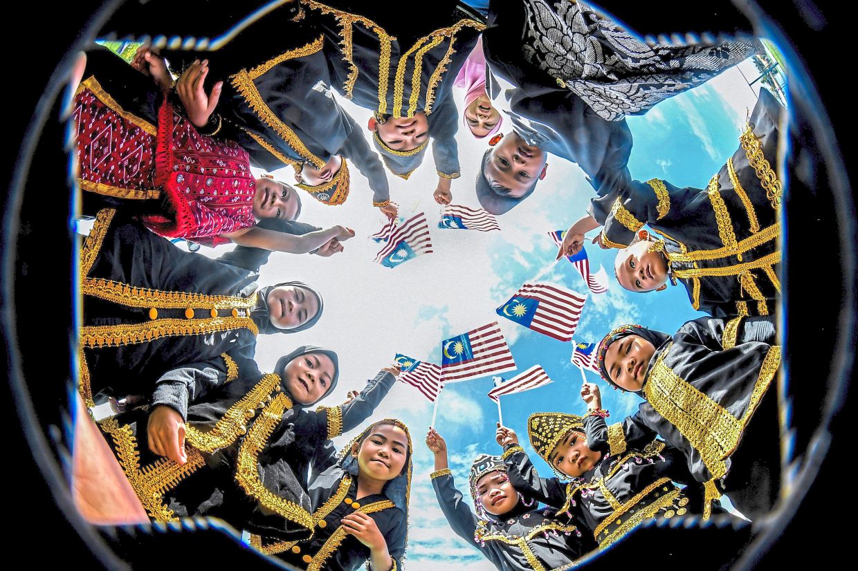Children from Tadika Kemas Kampung Paris 2 in Kinabatangan, Sabah, clad in their traditional outfits while proudly waving mini flags. — Photos: AZLINA ABDULLAH, ZHAFARAN NASIB/The Star and Bernama